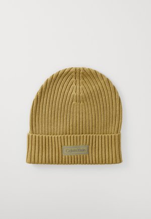 Tan geribbelde gebreide muts met omgeslagen rand en rechthoekige Calvin Klein logo patch in het midden vooraan.