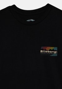 Black cotton t-shirt with a crew neckline, featuring a multicolored rectangular logo patch reading "Billabong Adventure Division."