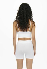 Hvid sømløs bralette og shorts sæt, tætsiddende design, blødt stof, tykke stropper, glat tekstur, rene linjer, minimalistisk stil.
