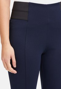 Námornícke športové legíny s hladkým, elastickým materiálom. Majú vysoký čierny pás s dvoma horizontálnymi švami pre zvýraznenie dizajnu.