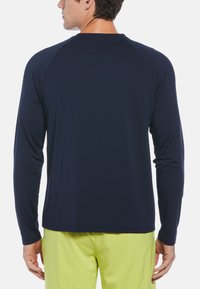 Marineblaue Langarmshirt mit glatter Textur und Raglanärmeln. Verfügt über einen Rundhalsausschnitt und wird mit leuchtend grünen Shorts kombiniert.