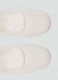 Chaussures en tissu blanc avec une texture lisse et un bout carré, présentant une large ouverture arrondie sur le bord supérieur. Pas de quincaillerie ni de motifs visibles.