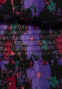 Bunt gemusterten Stoff mit schwarzen, lila und grünen abstrakten Mustern und horizontaler Raffungstextur.