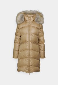Długa beżowa kurtka puchowa z przednim zamkiem błyskawicznym, kieszeniami na zamek oraz kapturem wyściełanym jasnobrązowym futerkiem z sztucznego futra.