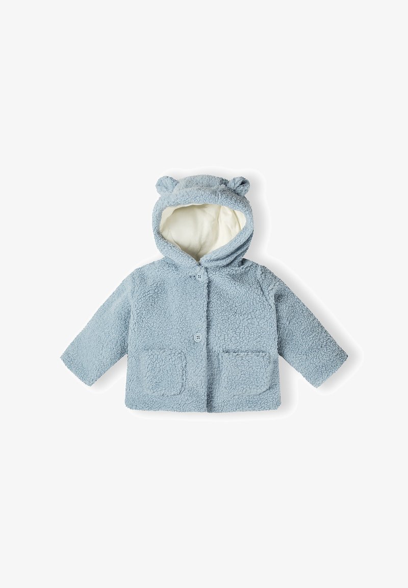 Veste pour tout-petit bleu clair, duveteuse, avec capuche et oreilles d’ours, deux poches avant et fermeture à boutons, doublure crème douce à l’intérieur de la capuche.