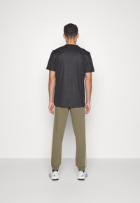 adidas Sportswear ESSENTIALS TAPERED CUFF 3-STRIPES  - Treniņtērpa apakšdaļas - olive strata