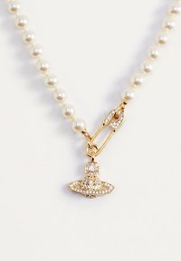 Collar de perlas con un broche de imperdible de oro y un colgante de oro con forma de planeta adornado con pedrería transparente.