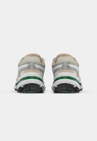 Baskets de sport blanches et grises avec des accents verts, présentant une tige en maille, des détails moulés et une semelle noire texturée. Vue arrière.
