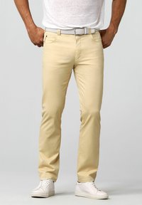 Lichtbeige chinos met een rechte pijpdesign, gemaakt van katoen, met voorzakken en een lichte geweven riem. Draagt met witte sneakers.