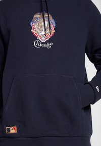 Marinblå hoodie med framficka, utrustad med broderad Chicago-logotyp och märke, texturerad tyg och ribbade muddar. Inkluderar MLB-märke.