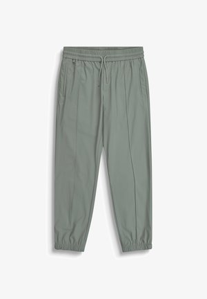 Lichtgrijs-groene joggingbroek met elastische tailleband en boorden, trekkoord, zijzakken en een klein metalen ringdetail aan de linkerkant.