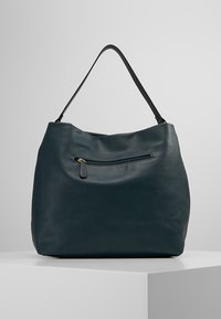 Grönblå läderväska med slapp design, texturerad yta, ett övre handtag och en framficka med dragkedja och guldfärgad dragkedjeförslutning.