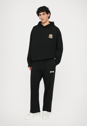 Black hoodie with front pocket and embroidered design. Black sweatpants with "BARROW" logo. Both made from soft fabric, paired with white sneakers.