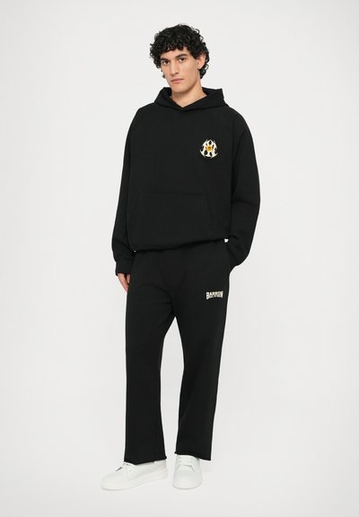 Zwarte hoodie met voorzak en geborduurd ontwerp. Zwarte sweatpants met "BARROW" logo. Beide gemaakt van zachte stof, gecombineerd met witte sneakers.