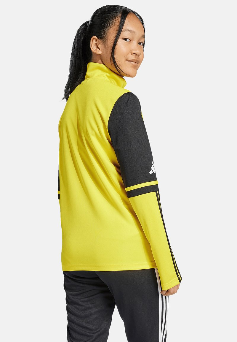 Gelbe Sportjacke mit schwarzen Ärmeln und Streifen. Hergestellt aus glattem, flexiblem Material. Verfügt über einen hohen Kragen und ein Logodesign am Ärmel.