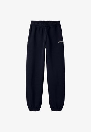 Pantalon de jogging noir avec taille élastique et poignets élastiques, avec un petit texte blanc "STUDIO" sur la cuisse droite.