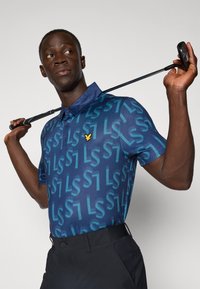 Blue polo shirt with a gradient "LS" pattern, short sleeves, and a button-up collar. Features a small yellow logo on the chest. Black pants.
