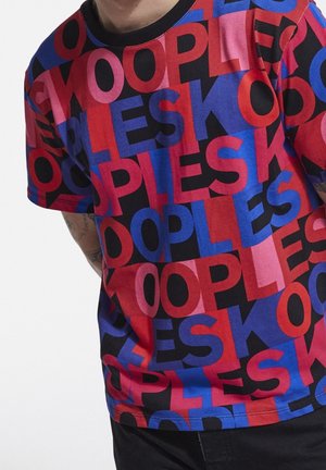 T-shirt avec des lettres audacieusement superposées en rouge, bleu, noir et rose formant un motif répétitif de "PEOPLESK."