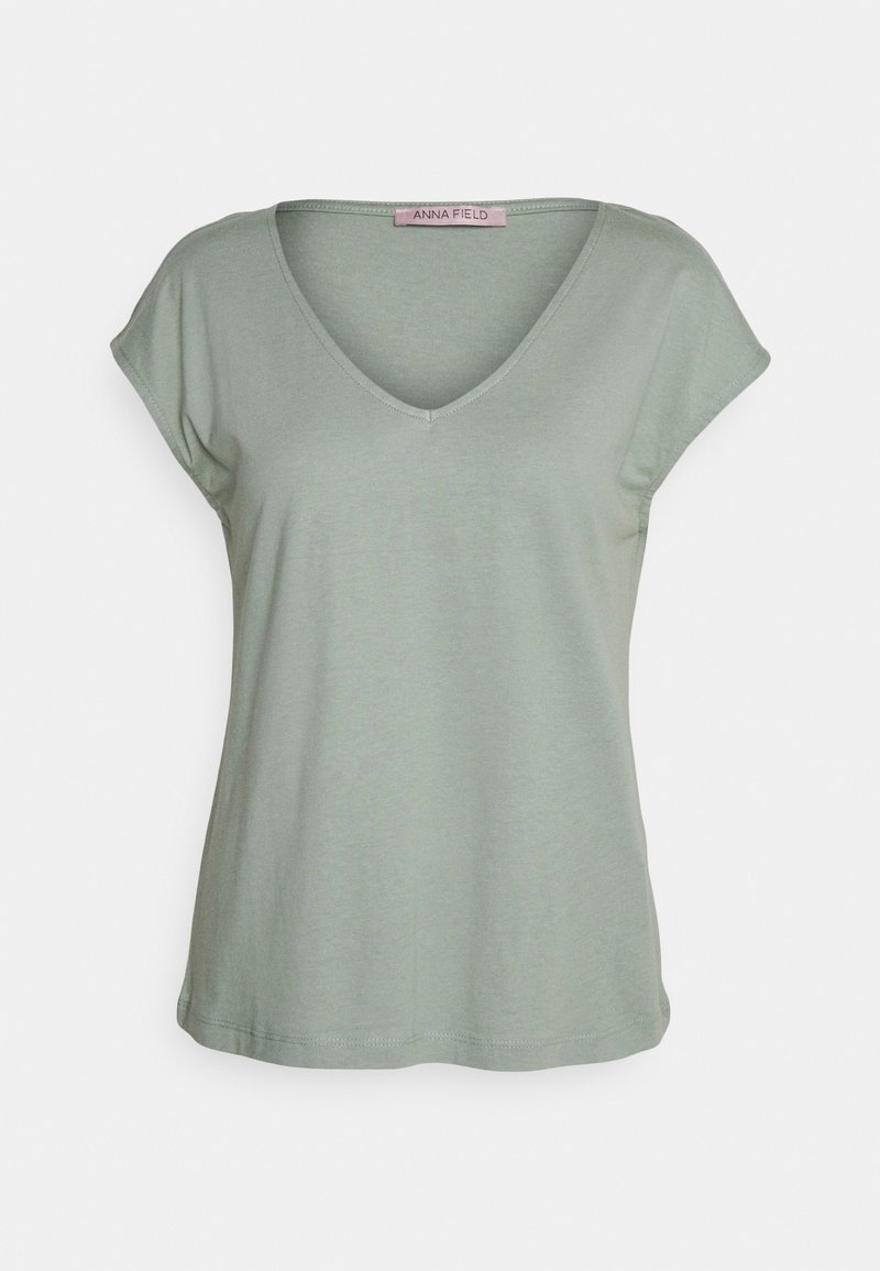 T-shirt femme à manches courtes vert clair avec col en V, coupe ample et design simple, présenté sur fond blanc uni.