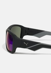Mustad sportlikud prillid gradient purple läätsedega, matte viimistlusega ja hõbedase Puma logo aktsendiga templil. Nurgeline raami disain.