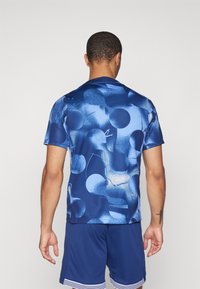 Korte mouw sportshirt in het blauw met een abstract patroon van verschillende tinten en texturen; gladde stof en moderne pasvorm.