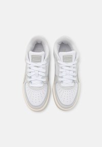 Fehér sportcipők szintetikus felsőrésszel, perforált orral, lapos fűzőkkel, világoskék részletekkel és gumitalppal. Márkalogó a nyelvén.