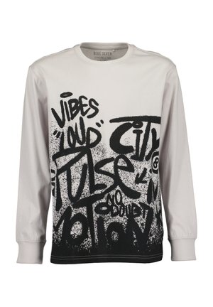 Hvid skjorte med lange ærmer med sort graffiti-stil tekst, inklusiv "Vibes", "Loud" og "Pulse" der dækker fronten.