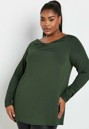 Donkergroene langwerpige top met gedrapeerde halslijn en aansluitende silhouette. Zacht, rekbaar materiaal met een gladde textuur en een naad aan de zijkant.
