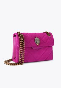 Roze suède handtas met een gekleed ontwerp, voorzien van een gouden kettingband en een decoratieve sluiting in de vorm van een vogel. Compact rechthoekige vorm.