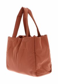 Sac fourre-tout rembourré de couleur rouille, doté de deux poignées robustes, d'une forme structurée et de détails de surpiqûres sur la surface.