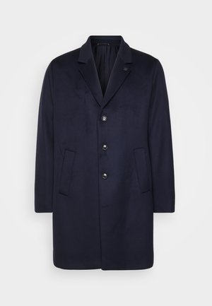 Granatowy wełniany płaszcz z klapami z wycięciem, sześcioma guzikami, dwoma bocznymi kieszeniami i lekko oversize'owym krojem. Gładka faktura, minimalistyczny design.