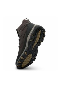 Botte de randonnée inclinée montrant la semelle robuste noire et marron avec des crampons profonds et une adhérence texturée pour la randonné en extérieur.