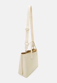 Borsa sintetica color crema con un design strutturato, dotata di una tracolla rimovibile, due manici e dettagli in metallo dorato.