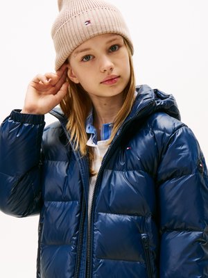 Chaqueta acolchada azul marino con secciones acolchadas, bolsillos con cremallera y capucha, combinada con un gorro de punto rosa claro que presenta un logotipo.