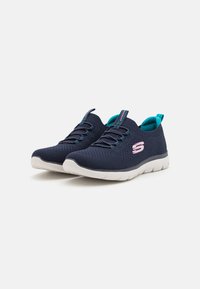 Zapatillas de malla marinas con suela blanca, que cuentan con cordones elásticos y acentos turquesa. Logotipo lateral en rosa. Diseño ligero para mayor comodidad.