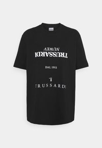 Camiseta de algodón negra con gran impresión blanca que presenta el texto "TRUSSARDI" y "DAL 1911", corte relajado, cuello redondo y mangas cortas.