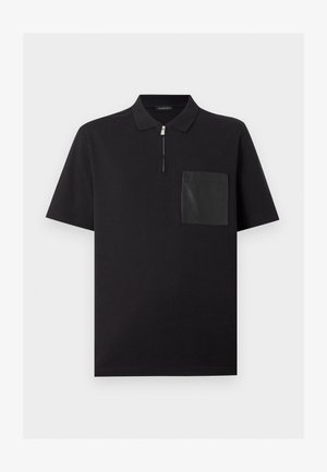 Črna polo majica s kratkimi rokavi, z zadrgo na ovratniku in kontrastnim teksturiranim žepom na levi strani prsi.