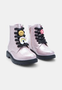 Stivaletti alla caviglia rosa glitterati con lacci neri, dotati di charms a forma di faccina sorridente e arcobaleno. Suole in gomma con battistrada prominente per una buona aderenza.