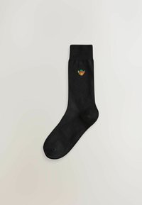 Sosete negre din bumbac cu mansetă cu nervuri. Prezintă un mic design brodat cu fața unui leu caraghios, purtând o podoabă de cap colorată.