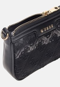 Borsa crossbody nera con una parte anteriore in rete testurizzata, accessori in oro e chiusura con zip. Presenta motivi geometrici in rilievo e dettagli con logo.