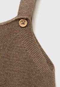 Tessuto marrone lavorato a maglia con un motivo testurizzato, caratterizzato da un dettaglio di bottone in legno sulla tracolla. Design semplice e funzionale.