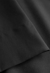 Musta kangas, jossa on sileä pinta ja hienovarainen raidoitus. Reunassa on tarkka ompelu.