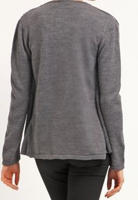 Maglione grigio realizzato in tessuto morbido, con collo rotondo, maniche lunghe e un retro leggermente svasato con un design testurizzato.