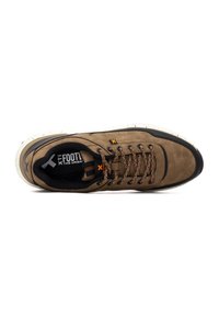 Zapatillas de ante marrón con detalles en negro, punta redondeada, cordones texturizados y una suela blanca moteada. Logo de la marca visible en la plantilla.