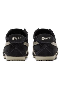 Černé semišové tenisky s béžovým pruhem, gumovou podrážkou a výrazným logem "Tiger" na patě. Texturovaná zadní část s prošitím.