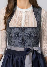 Traditionelles Kleid mit einem marineblauen, gemusterten Oberteil, weißen Spitzenärmeln und einem plissierten, marineblauen Rock mit einer satinartigen Schleife in der Taille.