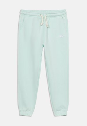 Pantalon de jogging bleu clair avec taille élastique, cordon blanc, poches latérales, poignets élastiques et petit logo blanc New Balance sur la cuisse gauche.