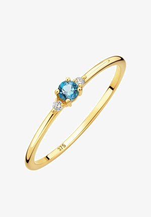 Zlatý prsteň s centrálnym okrúhlym akvamarínovým kameňom, po oboch stranách s dvoma malými okrúhlymi čírymi kameňmi, s hladkým, lesklým prstienkom.