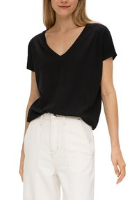 Czarny krótki rękaw bluzka z dekoltem w serek o fakturowanym wyglądzie, noszona z białymi spodniami z wysokim stanem, prezentująca luźny krój i opadający fason.