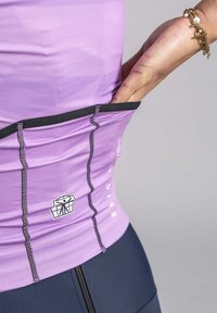 Purple athletic top with textured fabric, featuring a black waistband and a side pocket. Garment includes a logo and stitched details.
